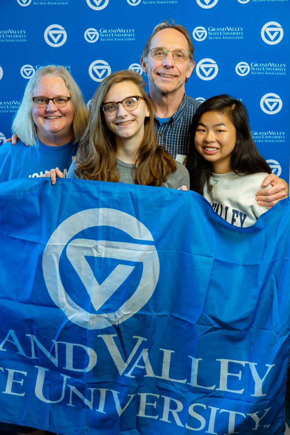 A family photo of alumni holding the GV flag